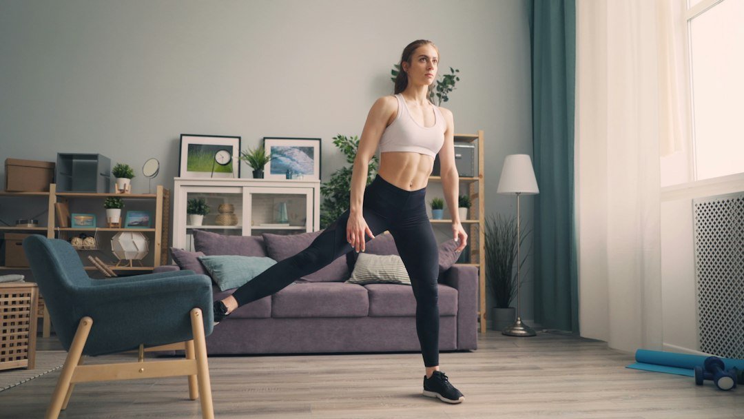 Person performing standing marches by lifting one knee at a time during a home workout